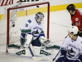 Vancouver Canucks goalie Eddie Lack, left, from Sweden, lets in a goal from Calgary Flames' Dennis Wideman (not pictured) as Jiri Hudler, from the Czech Republic, looks on during first period NHL first round playoff hockey action in Calgary, Tuesday, April 21, 2015.THE CANADIAN PRESS/Jeff McIntosh