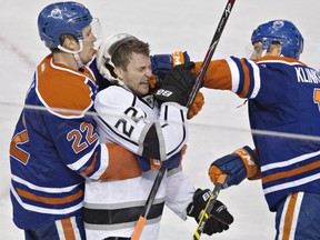 Los Angeles Kings' Trevor Lewis (22) is punched by Edmonton Oilers' Rob Klinkhammer (12) as Keith Aulie (22) holds Lewis during second period NHL hockey action in Edmonton, Alta., on Tuesday April 7, 2015. THE CANADIAN PRESS/Jason Franson