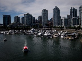 A water taxi decorated with a Canadian flag on the roof travels on False Creek as boats are moored in a marina near Yaletown condo towers in Vancouver, B.C., on Sunday July 13, 2014. Statistics Canada's latest survey found that Vancouver is Canada's unhappiest city.