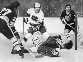 Vancouver Canucks goalie Cesare Maniago stops Boston Bruins Earl Anderson while Canucks Dave Fortier and Bruins Johnny Bucyk look on during NHL action at the Pacific Coliseum, December 30, 1975.