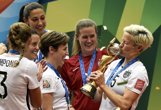 USA midfielder Megan Rapinoe (R) kiss the trophy next to USA defender Meghan Klingenberg (L) as she celebrates with teammates after their victory in the final football match between USA and Japan during their 2015 FIFA Women's World Cup at the BC Place Stadium in Vancouver on July 5, 2015.  AFP PHOTO / FRANCK FIFEFRANCK FIFE/AFP/Getty Images