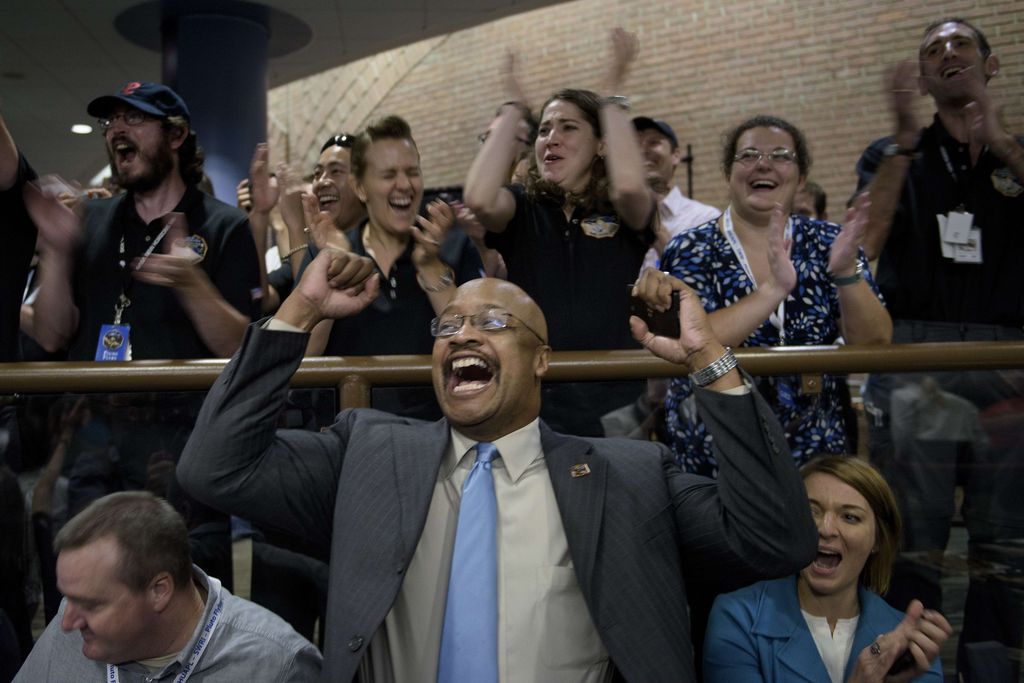 NASA and project staff react with others as telemetry is received from the New Horizons probe at the Johns Hopkins University Applied Physics Laboratory in Laurel, Maryland on July 14, 2015. The New Horizons interplanetary space probe reestablished contact with NASA after safe passage completing its closest approach fly-by of Pluto making the United States the first to explore the dwarf planet. AFP PHOTO/BRENDAN SMIALOWSKIBRENDAN SMIALOWSKI/AFP/Getty Images