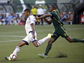 Vancouver Whitecaps defender Christian Dean, left, passes down field as Portland Timbers forward Darlington Nagbe pursues during the first half of an MLS soccer game in Portland, Ore., Saturday, July 18, 2015. (AP Photo/Don Ryan)