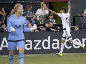 Vancouver Whitecaps midfielder Matias Laba celebrates scoring a goal, as he runs toward his bench during the second half of an MLS soccer match against the Portland Timbers in Portland, Ore., Saturday, July 18, 2015. Celebrating at left is Vancouver goalkeeper David Ousted. (AP Photo/Don Ryan)