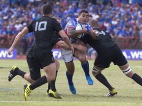 Samoa's Tusiata Pisi, center, tries to run through a defense of New Zealand All Blacks during their rugby union match at Apia Park in Apia, Samoa, Wednesday, July 8, 2015. New Zealand won the match 25-16 in the All Blacks' first-ever test match in the Pacific Island nation. (Dean Purcell/New Zealand Herald via AP)
