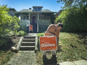 Don Davies, MP for Vancouver-Kingsway and the NDP's incumbent candidate for the riding, puts up election signs, along with outreach coordinator Wei Zhang, on E 23rd Ave. in Vancouver on Monday.