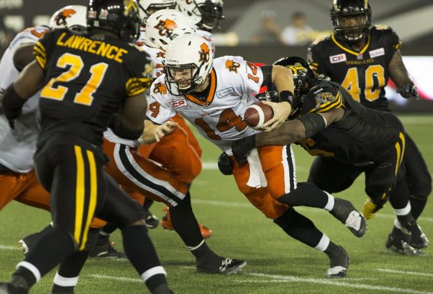 B.C. Lions quarterback Travis Lulay (14) is taken down by Hamilton Tiger-Cats defensive tackle Bryan Hall (6) during the second half of CFL football action in Hamilton on Saturday, August 15, 2015. The Tiger-Cats defeated the Lions 52-22. THE CANADIAN PRESS/Peter Power