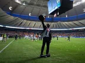 Vancouver Whitecaps' Pa-Modou Kah, of Norway, rides a self balancing electric transporter as he hoists the Voyageurs Cup trophy after the MLS team defeated the Montreal Impact to win the Canadian Championship soccer final in Vancouver, B.C., on Wednesday August 26, 2015. THE CANADIAN PRESS/Darryl Dyck