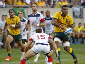 Australia's Wycliff Palu, right, looks to pass the ball against United States' Blaine Scully, center, during the first half of an international rugby test match at Soldier Field, Saturday, Sept. 5, 2015, in Chicago. (AP Photo/Kamil Krzaczynski)