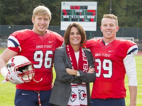 From UBC¹s blue and gold, to SFU¹s red, white and blue, Theresa Hanson
shows off her new colours as the Clan¹s new athletic director, flanked by
football players Cameron Cross (96) and Chad Heerspink (39). Hanson, 51,
is a former Clan women¹s basketball assistant coach and begins her new
posting on Dec. 14. (Photo -- Ron Hole/SFU athletics)