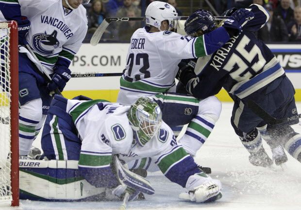 Vancouver Canucks' Jacob Markstrom, front, of Sweden, covers the puck as teammate Alexander Edler, center, and Columbus Blue Jackets' William Karlsson, of Sweden, vie for position during the second period of an NHL hockey game Tuesday, Nov. 10, 2015, in Columbus, Ohio. The Canucks won 5-3. (AP Photo/Jay LaPrete)