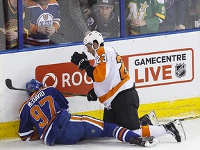 Edmonton centre Connor McDavid (97) hits the boards hard after being checked by Philadelphia defenceman Brandon Manning at Rexall Place Tursday. He's out long-term with a shoulder injury.