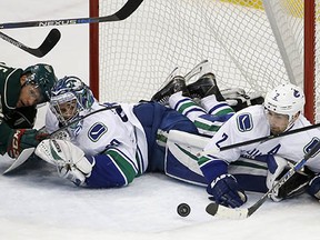 Jason Pominville, Ryan Miller and Dan Hamhuis watch the puck get cleared away from the front of the Canucks' net.