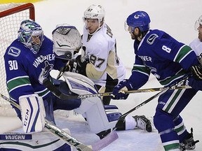 Ryan Miller keeps the puck out as Sidney Crosby (centre) and Chris Tanev look for a rebound.