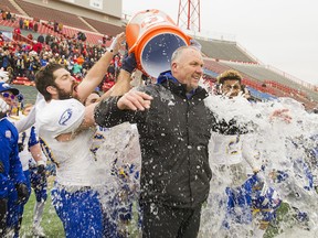 UBC Thunderbirds’ head coach Blake Nill gets a traditional victory shower on the field from his players after the No. 6-ranked ‘Birds shocked the host, No. 1-ranked, undefeated Calgary Dinos 34-26 in the Canada West Hardy Cup championship at McMahon Stadium on Saturday. UBC is now one victory away from playing in the Vanier Cup national final. (Richard Lam, UBC athletics)