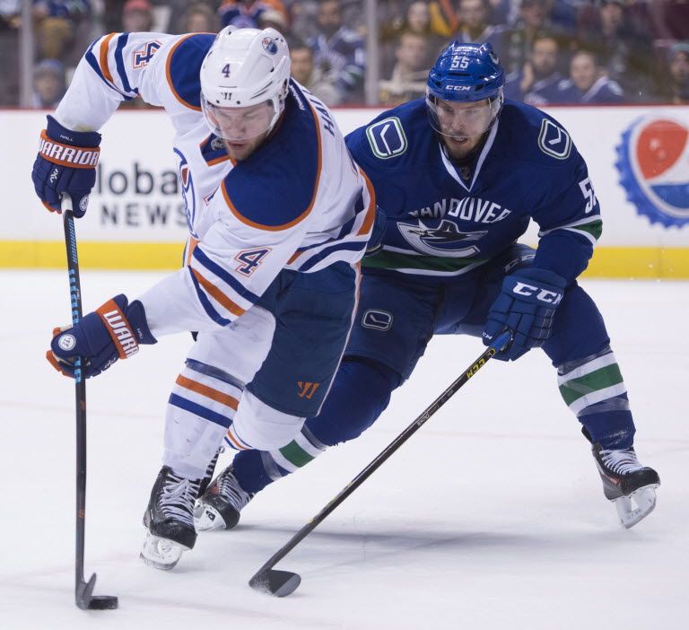 Vancouver Canucks defenceman Alex Biega (55) fights for control of the puck with Edmonton Oilers left wing Taylor Hall (4) during first period NHL action Vancouver, B.C. Saturday, Dec. 26, 2015. THE CANADIAN PRESS/Jonathan Hayward  