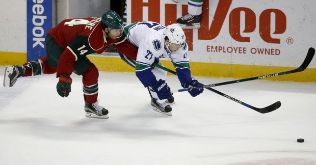 Minnesota Wild right wing Justin Fontaine (14) and Vancouver Canucks defenseman Ben Hutton, right,  chase the puck during the first period of an NHL hockey game in St. Paul, Minn., Tuesday, Dec. 15, 2015. (AP Photo/Ann Heisenfelt)