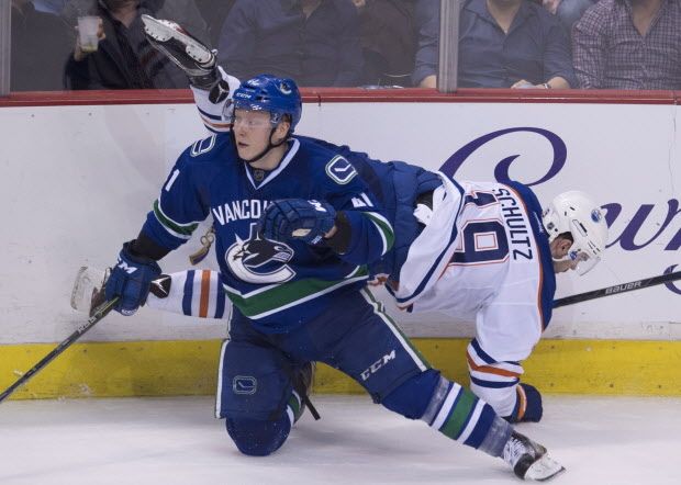 Vancouver Canucks left wing Ronalds Kenins (41) goes into the boards with Edmonton Oilers defenceman Justin Schultz (19) during second period NHL action Vancouver, B.C. Saturday, Dec. 26, 2015. THE CANADIAN PRESS/Jonathan Hayward
