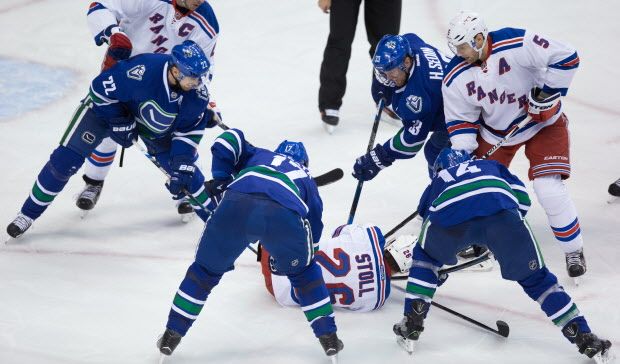 Vancouver Canucks' Daniel Sedin, of Sweden, from left, Radim Vrbata, of the Czech Republic, Henrik Sedin, of Sweden, and Alex Burrows dig away at the puck under New York Rangers' Jarret Stoll, centre, as he covers it up while teammate Dan Girardi, right, watches during third period NHL hockey action, in Vancouver, on Wednesday, Dec. 9, 2015. The play landed Stoll a delay-of-game penalty. THE CANADIAN PRESS/Darryl Dyck