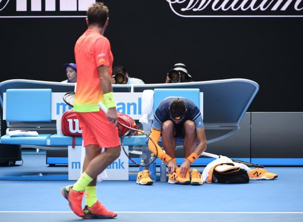 Canada's Milos Raonic (R) changes his shoes during his men's singles match against Switzerland's Stanislas Wawrinka (L) on day eight of the 2016 Australian Open tennis tournament in Melbourne on January 25, 2016. AFP PHOTO / WILLIAM WEST-- IMAGE RESTRICTED TO EDITORIAL USE - STRICTLY NO COMMERCIAL USEWILLIAM WEST/AFP/Getty Images