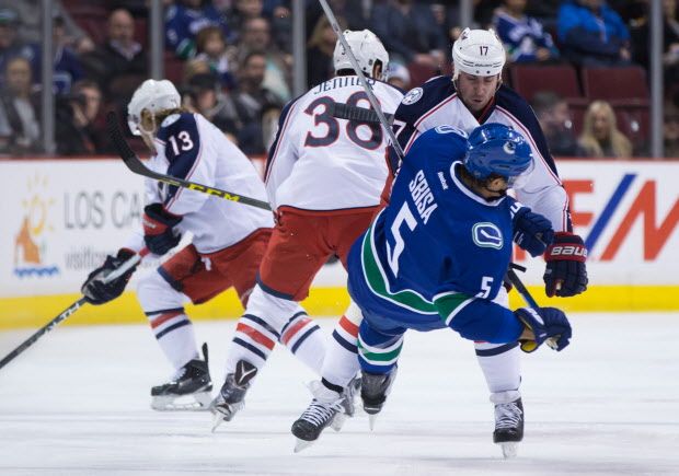 Columbus Blue Jackets' Brandon Dubinsky, back right, checks Vancouver Canucks' Luca Sbisa, of Italy, during the first period of an NHL hockey game in Vancouver, B.C., on Thursday February 4, 2016. THE CANADIAN PRESS/Darryl Dyck