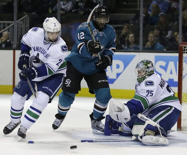 Vancouver Canucks goalie Jacob Markstrom, right, blocks a shot from San Jose Sharks' Joel Ward (42) during the third period of an NHL hockey game Saturday, March 5, 2016, in San Jose, Calif. At left is Canucks' Dan Hamhuis (2). Vancouver won 4-2. (AP Photo/Ben Margot)