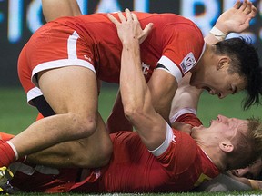 Canada's Nathan Hirayama, top, congratulates John Moonlight after he scored the tying try at the final horn against France. Hirayama nailed the convert to give Canada the win.
