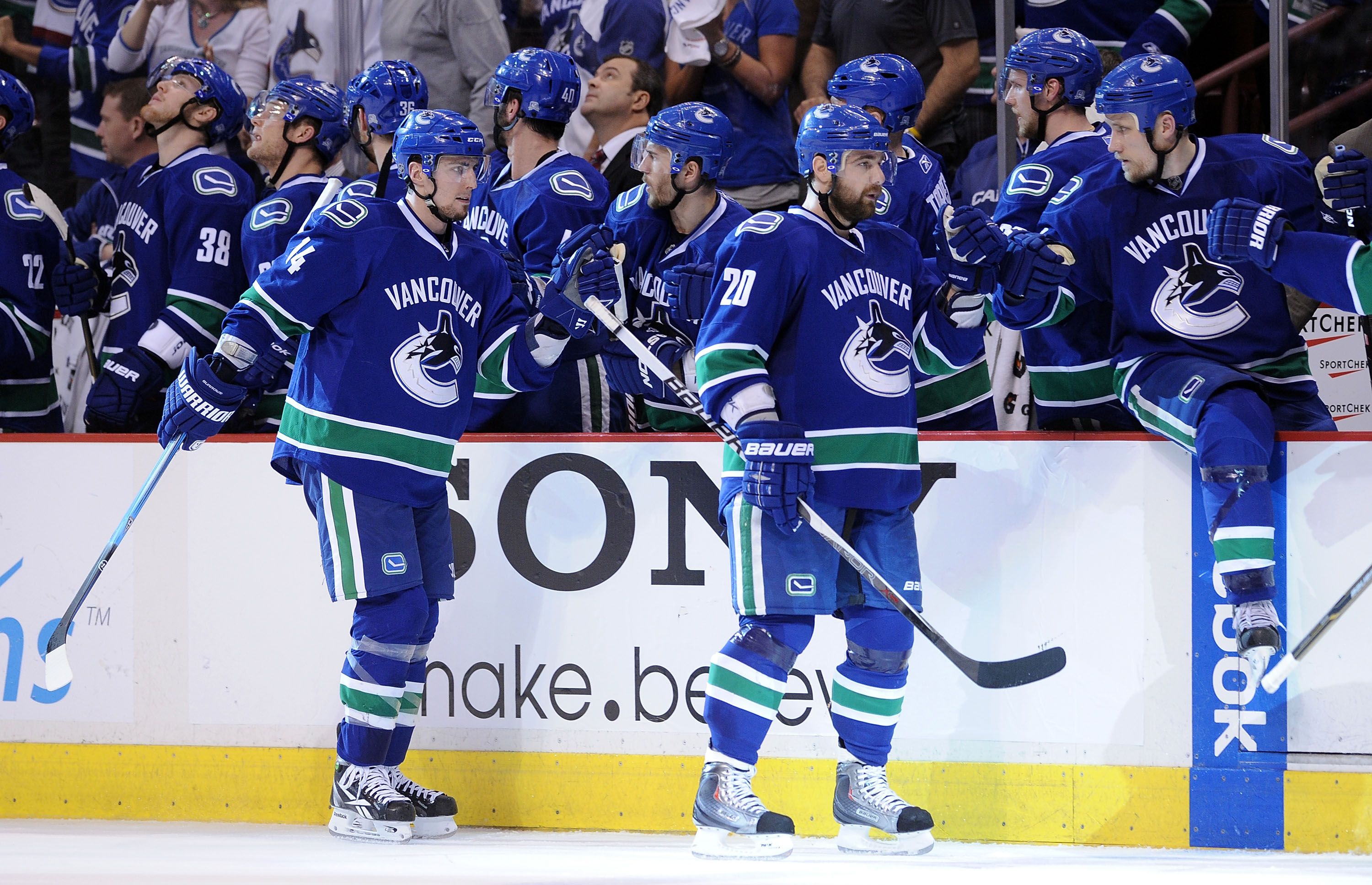 VANCOUVER, CANADA - MAY 18: Alex Burrows #14 and Christopher Higgins #20 of the Vancouver Canucks skate by the Canucks bench to celebrate with teammates after Higgins scored a goal in the third period in Game Two of the Western Conference Finals against the San Jose Sharks during the 2011 Stanley Cup Playoffs at Rogers Arena on May 18, 2011 in Vancouver, British Columbia, Canada. The Canucks defeated the Sharks 7-3. (Photo by Harry How/Getty Images)