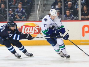 Ben Hutton of the Vancouver Canucks plays the puck as Blake Wheeler of the Winnipeg Jets gives chase during first period action at the MTS Centre on November 18, 2015 in Winnipeg. The Jets defeated the Canucks 4-1. The teams meet for a second time this season in Vancouver tonight.  (Photo by Darcy Finley/NHLI via Getty Images)
