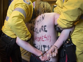 A protester gets taken inside by police at the Toronto courthouse on Thursday during Jian Ghomeshi's acquittal.