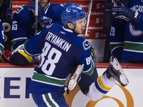 Nikita Tryamkin checks  Scottie Upshall into the Canucks' bench during third period NHL hockey action in Vancouver on Saturday, March 19, 2016. THE CANADIAN PRESS/Ben Nelms