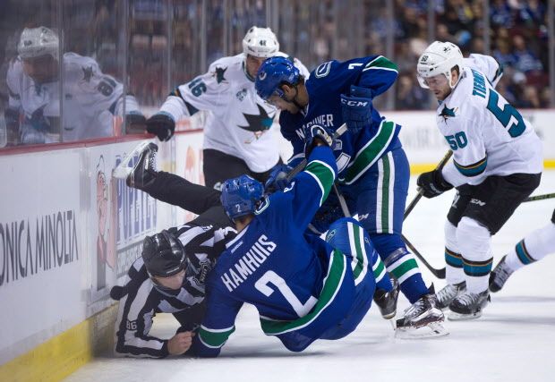 Linesman Brad Lazarowich, left, collides with Vancouver Canucks' Dan Hamhuis (2) as Linden Vey (7) digs for the puck against San Jose Sharks' Chris Tierney (50) and Roman Polak (46), of the Czech Republic, during first period NHL hockey action, in Vancouver on Sunday, Feb. 28, 2016. THE CANADIAN PRESS/Darryl Dyck
