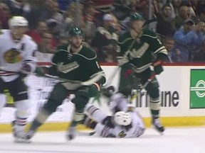 Chicago's Duncan Keith (lying down) swings his stick into the face of Minnesota's Charlie Coyle Tuesday night in Minnesota.
