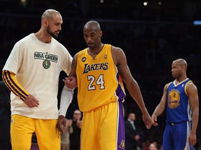 Robert Sacre helps Kobe Bryant off the court during a 2013 game at Staples Centre. (Getty Images photo)