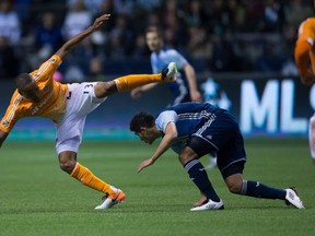 Houston Dynamo's Ricardo Clark, left, falls over Vancouver Whitecaps' Matias Laba during the first half of an MLS soccer game in Vancouver, B.C., on Saturday March 26, 2016. THE CANADIAN PRESS/Darryl Dyck