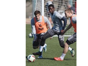 Alphonso Davies is defended by Brett Levis, right, and Daniel Haber, left, at the Whitecaps’ training camp. Marc Weber/PNG