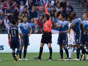 Vancouver Whitecaps' Matias Laba, second left, receives a red card from referee Jair Marrufo during the first half.