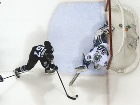 Vancouver Canucks goalie Ryan Miller (30) blocks a shot from San Jose Sharks center Tommy Wingels (57) during the first period of an NHL hockey game Thursday, March 31, 2016, in San Jose, Calif. (AP Photo/Tony Avelar)