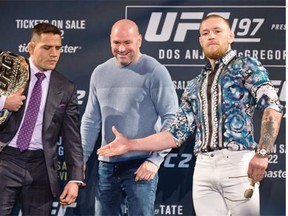 UFC 197 fighter Rafael dos Anjos, left, looks as Connor McGregor extends a hand as UFC President Dana White looks on in Las Vegas on Wednesday. The two joined a press conference featuring Holly Holm and Miesha Tate at the MGM Grand.