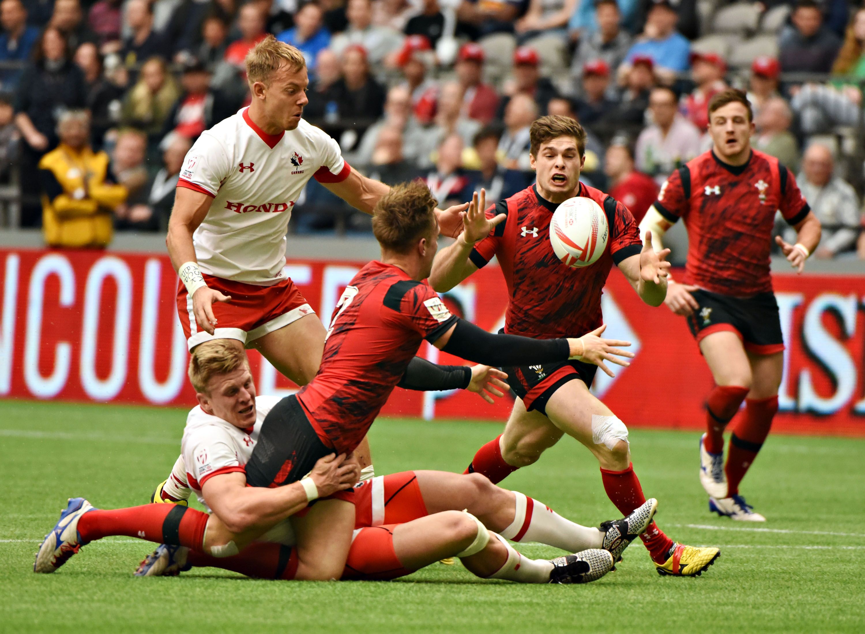 Chris Knight (C) of Wales grabs the ball and runs for a try in a 26-19 win over Canada (in white)  during HSBC World Rugby Sevens Series action in Vancouver, BC, Canada, March 12, 2016.  / AFP / Don MacKinnon        (Photo credit should read DON MACKINNON/AFP/Getty Images)
