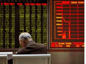 An investor sits near a display board showing the plunge in the Shanghai Composite Index at a brokerage in Beijing on Thursday.   — The Associated Press