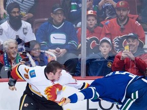 Luca Sbisa (right) gets into a spirited bout with Calgary Flames’ Micheal Ferland on Saturday night with his mother watching. She did not approve.