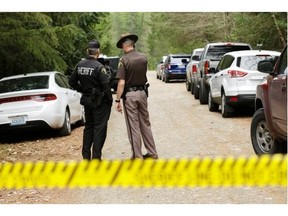 Mason County Sheriff's Chief Criminal Deputies Russ Osterhout, left, and Ryan Spurling, right, stand on a road near the scene of a fatal shooting Friday, Feb. 26, 2016, near Belfair, Wash.  A gunman who killed four people in rural Washington state called an officer he previously encountered to say he shot his family, leading to an hours long standoff at a home Friday that ended with his suicide, authorities said.