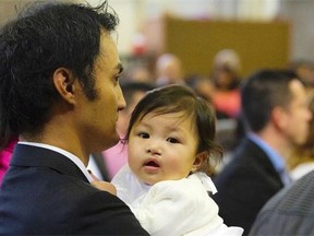 Neptali De Rama holds his daughter Emily at her baptism in Ontario in December.   — PNG