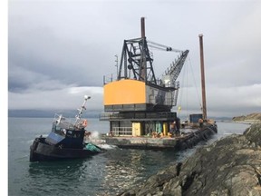 A barge carrying a crane is pulled from the rocks near Dallas Road and Olympia Avenue Thursday morning.