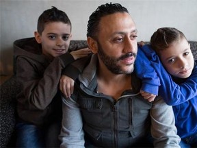 Newly arrived Syrian refugees Ahmad Hwichan, centre, and his sons Louai, left, 11, and Qusai, right, 8, pose for a photograph at a hotel where they're living temporarily in Vancouver on Tuesday, Jan. 12, 2016. Ahmad was attending a welcoming ceremony last Friday when about a dozen people were pepper sprayed by a man on a bicycle.