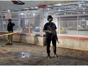 Pakistani police officers stand guard at the site of a bomb blast in a park in Lahore, Pakistan, Sunday, March, 27, 2016. A bomb blast in a park in the eastern Pakistani city of Lahore has killed tens of people and wounded scores, a health official said.