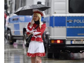 A female reveler walks in the rain in front of police cars during the start of the street carnival in Cologne, Germany, on Thursday, Feb. 4, 2016. After a string of robberies and sexual assaults on New Year's Eve in the city that police say were committed largely by foreigners, German authorities are keen to avoid a repeat of those events during the five-day street party.