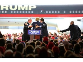 Security personnel surround Republican presidential candidate Donald Trump after a man tried to rush the stage during a campaign rally in Vandalia, Ohio, outside of Dayton, on Saturday, March 12, 2016. The man was stopped and Trump continued with his speech. (Carrie Cochran/The Cincinnati Enquirer via AP) MANDATORY CREDIT; NO SALES
