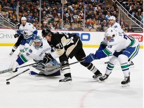 Pittsburgh’s Evgeni Malkin battles Canucks goalie  Ryan Miller and Emerson Etem, right, in a game in which Vancouver blew a 3-1 third-period lead Saturday.    — Getty Images